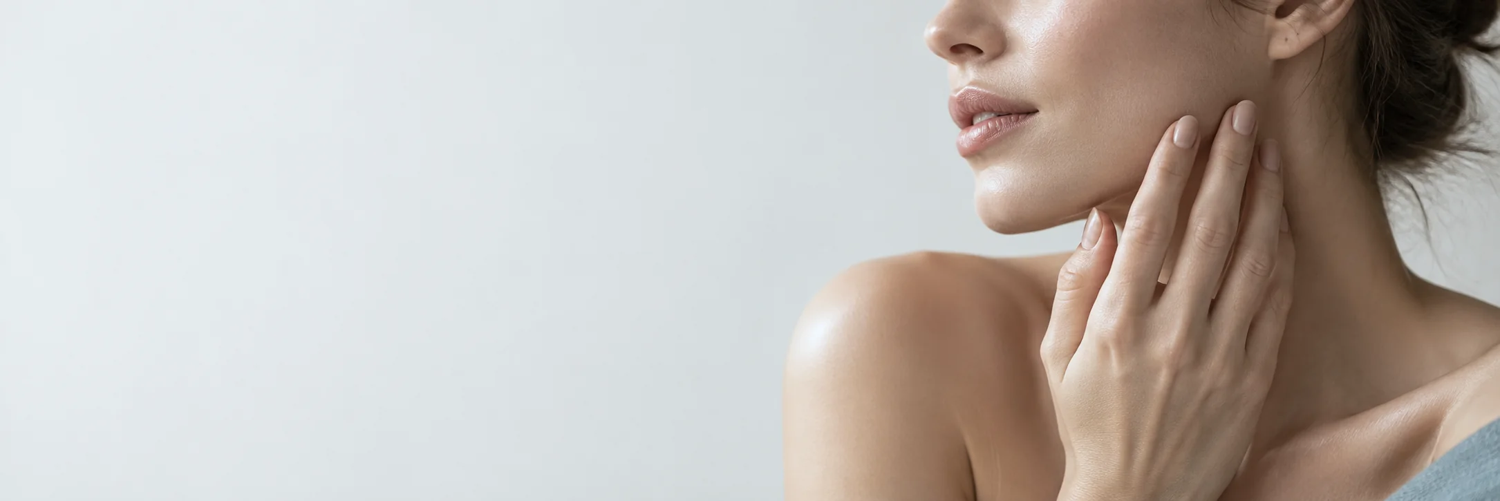 Profile of a woman resting her fingertips along her jaw against a soft ivory background