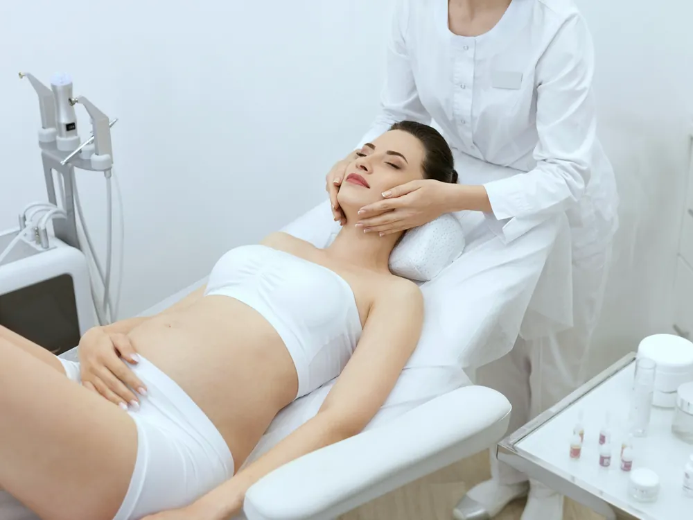 A client resting on a treatment bed beside body contouring equipment